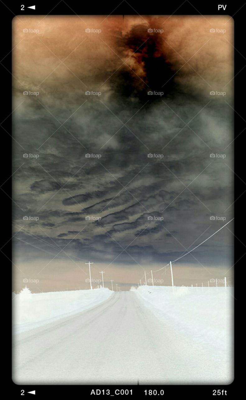 Ominous Country Road. I was cruising down a gravel road when I noticed the clouds loomed like fingers across the sky. I took some pics and used the filters on my phone to create what you see here.