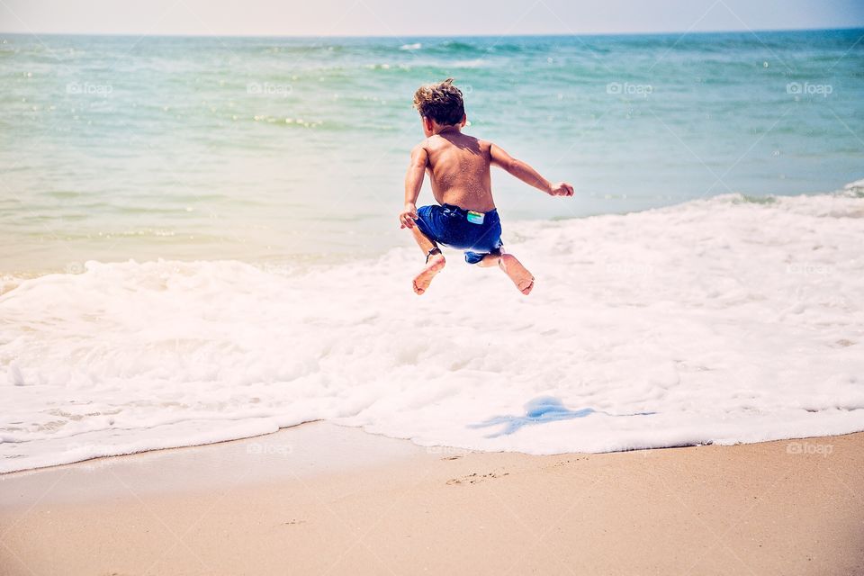 Boy jumping at sea
