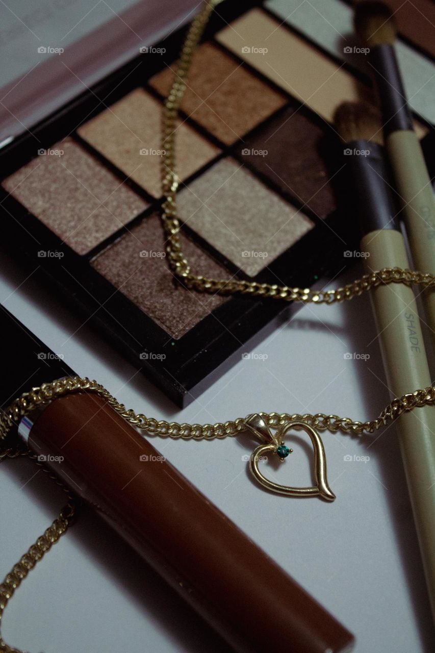 Natural colors of beauty products with a gold chain emerald heart necklace.