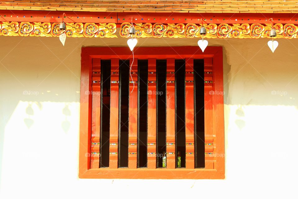 Red window on white wall in the temple.