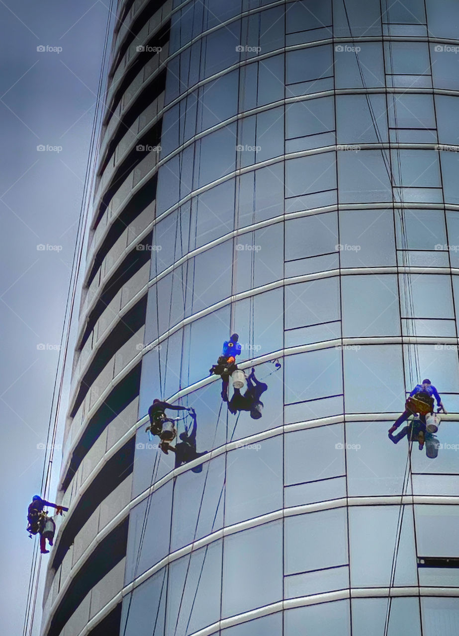 Window washers suspended on the facade of a steel and glass skyscraper