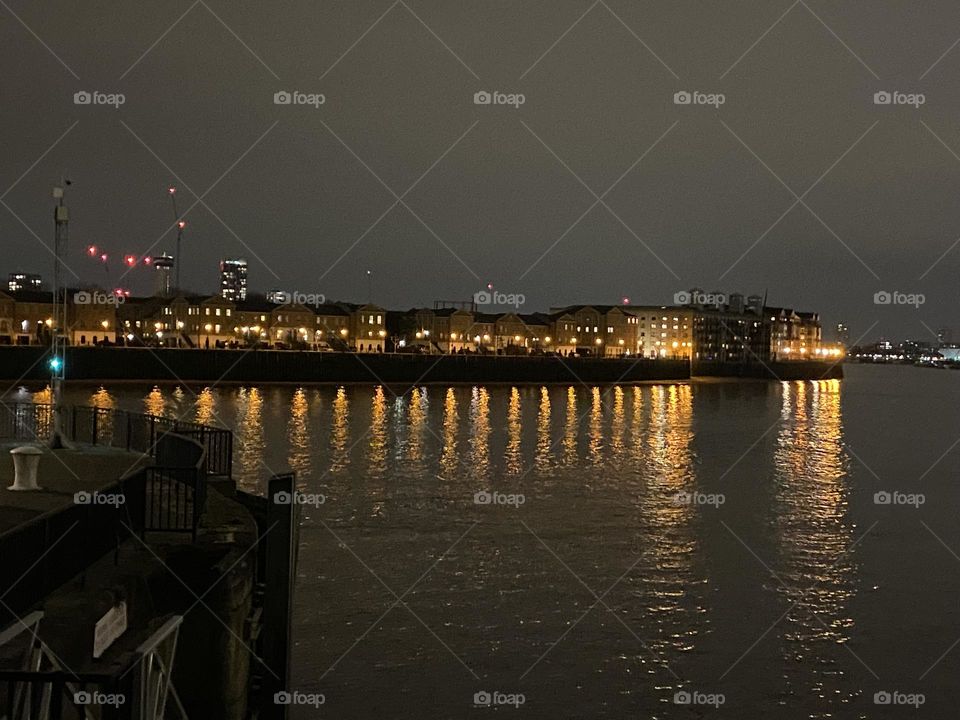 Buildings with illuminated windows during evening and reflection at water