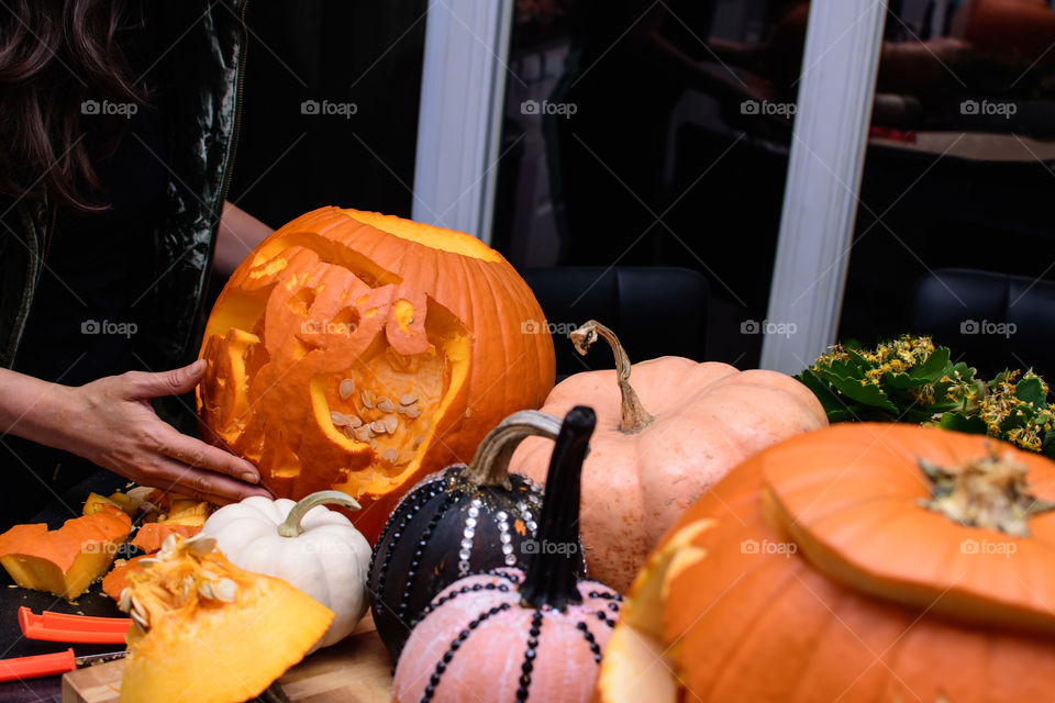 Pumpkin carving decorative Halloween cute dog Jack o’lantern carved pumpkin on preparation table indoors with pumpkin carving tools, white pumpkins, pumpkin seeds and arts and craft painted pumpkins 