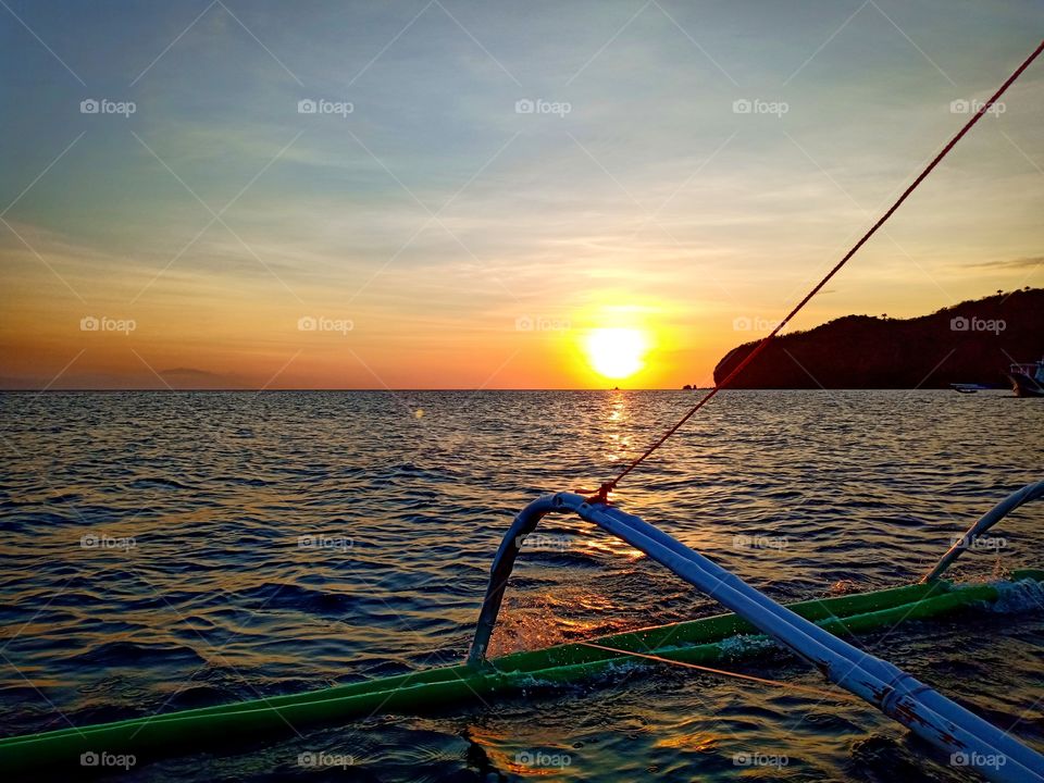 Golden sun meeting the horizon, spreading orange to yellow hues - Masasa Beach Batangas, Philippines