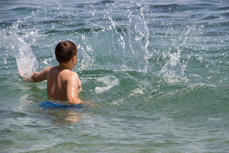 Boy playing with the water in the sea