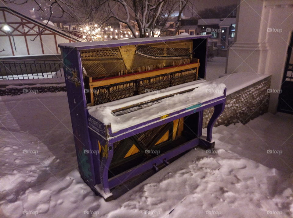 old idle voilet piano under snow in the evening lights