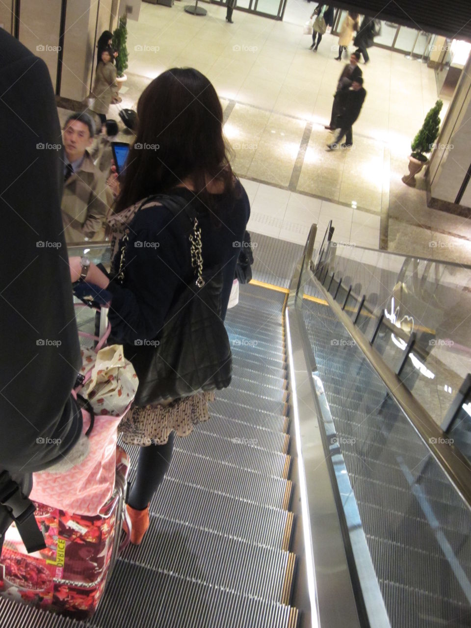 Woman Going Down Escalator, Tokyo Station, Japan.  Modern Fashion.  City Life, Commuters. Businesswoman.