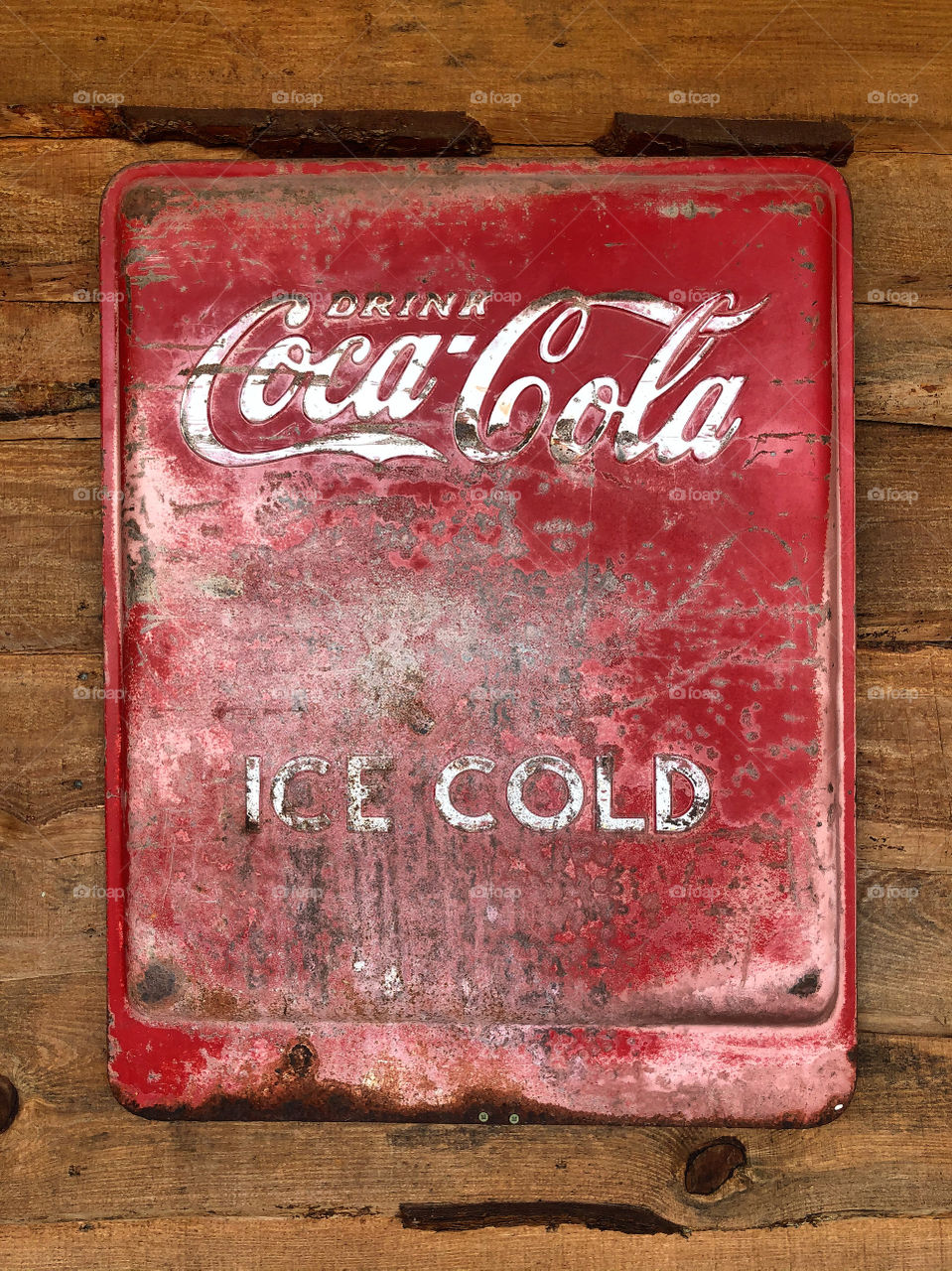 Vintages aged Coca-Cola sign on a wooden wall. 