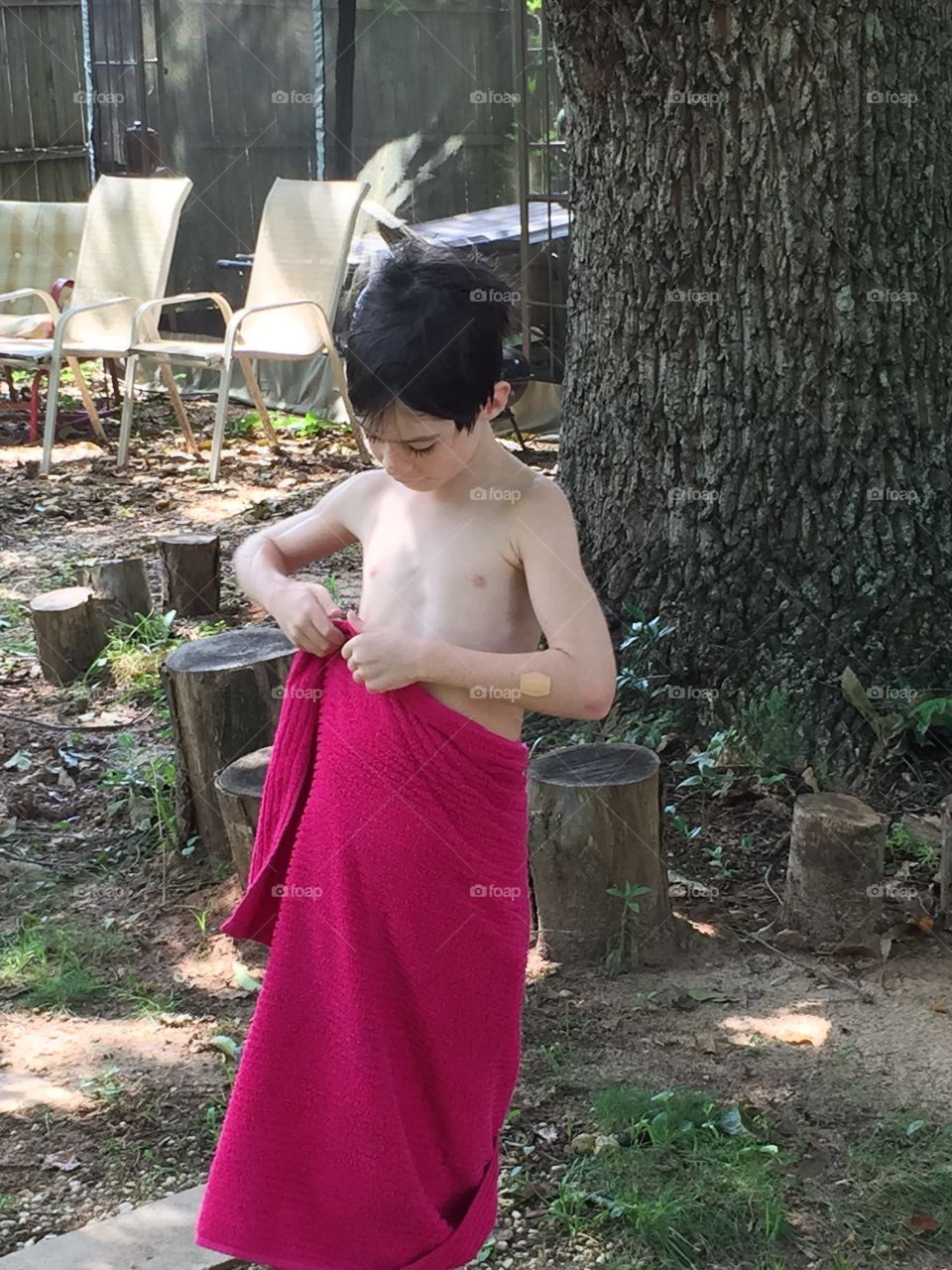 6 year old boy putting his towel around him after swimming.