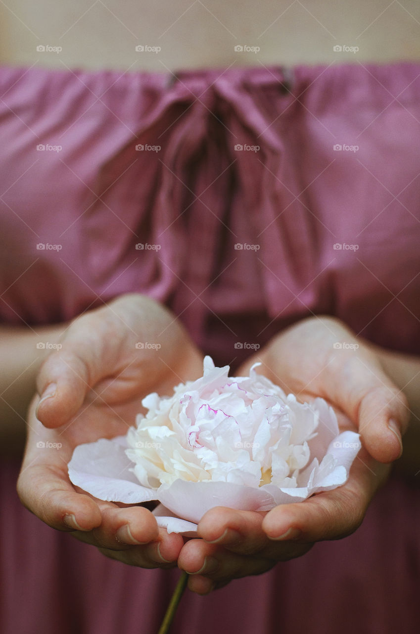 Young woman holding a beautiful pink fresh peonies in her hands in the garden. Lifestyle. Spring background.