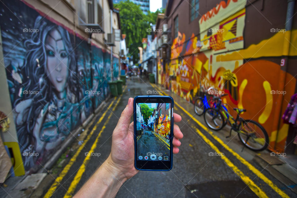 exploring singapore and taking photo with a phone of the mural art paiting in Singapore