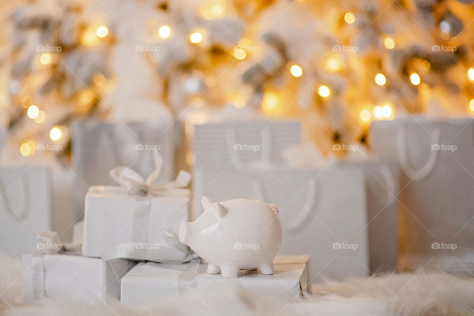 piggy bank with 100 dollars banknote in festive New Year atmosphere of scenery.  Magical bokeh with Christmas tree and bright lights.