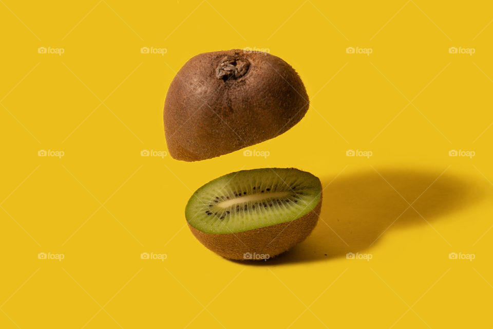 Kiwi fruit sliced on half with one half floating. Creative fruit concept