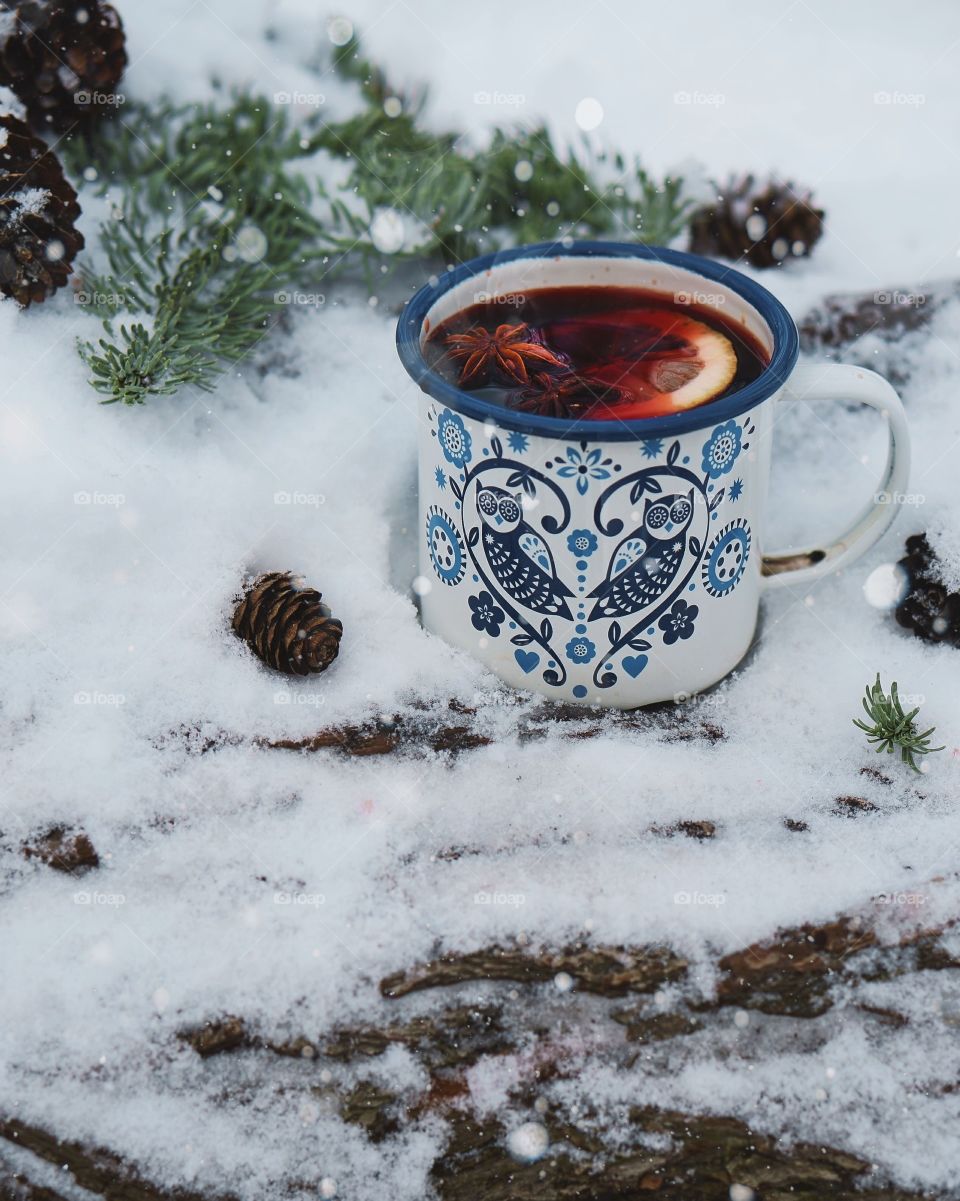 mug with hot mulled wine in snowy forest