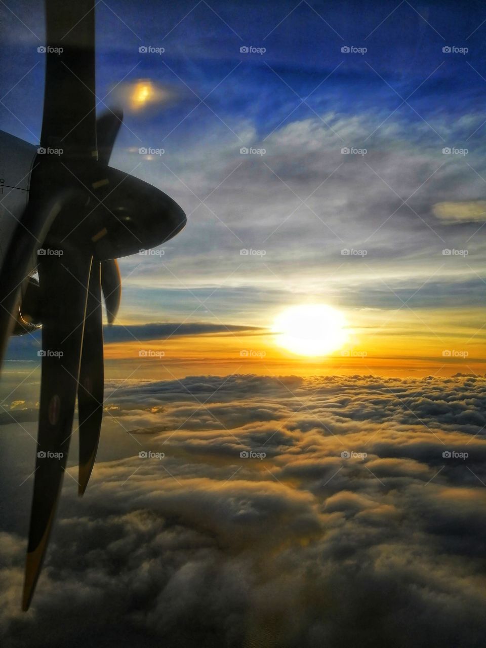 A breathtaking sunset view and sea of clouds while riding on a plane, showing the airplane propeller in action.