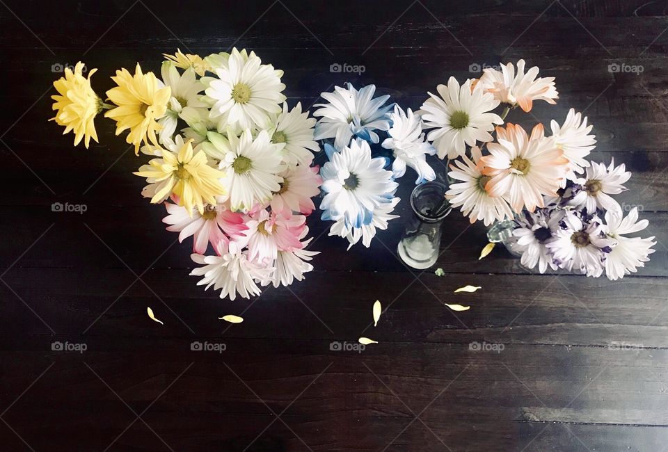 Colorful, Bright and beautiful flowers displayed in vases on the wooden table 