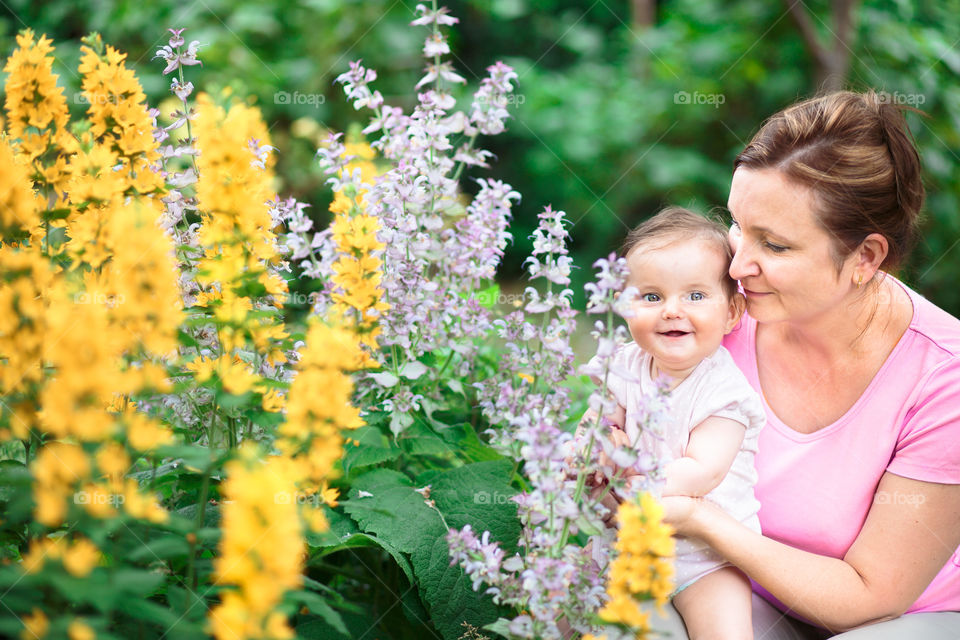 Smiling mother with her baby near flowering plants