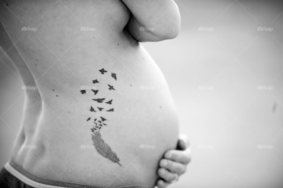 New Beginning . A soon to be new mother shows off her pregnant belly and tattoo. 