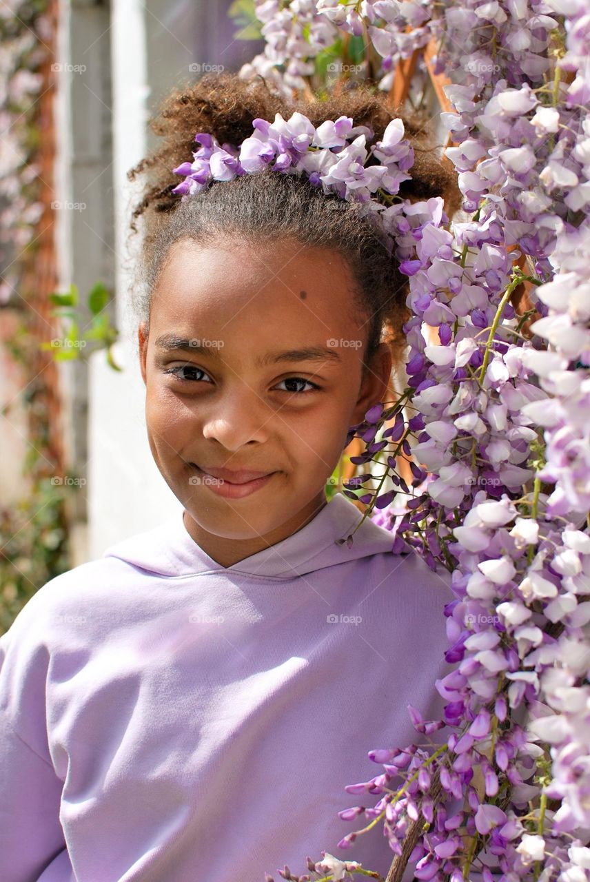 Teenage girl posing with wisteria plant