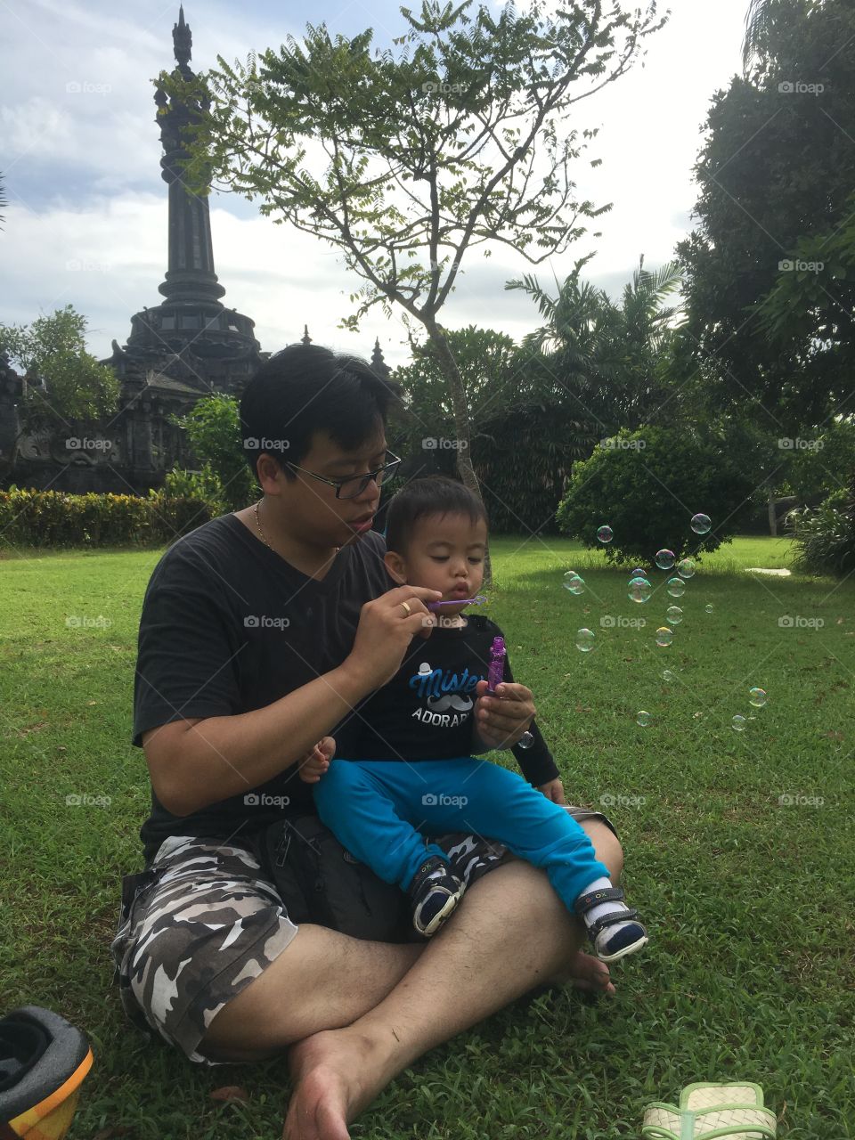 Father and son playing with bubbles in garden