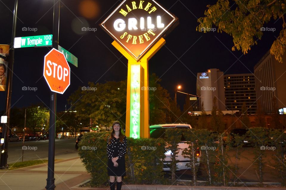 Woman standing near stop sign board at night