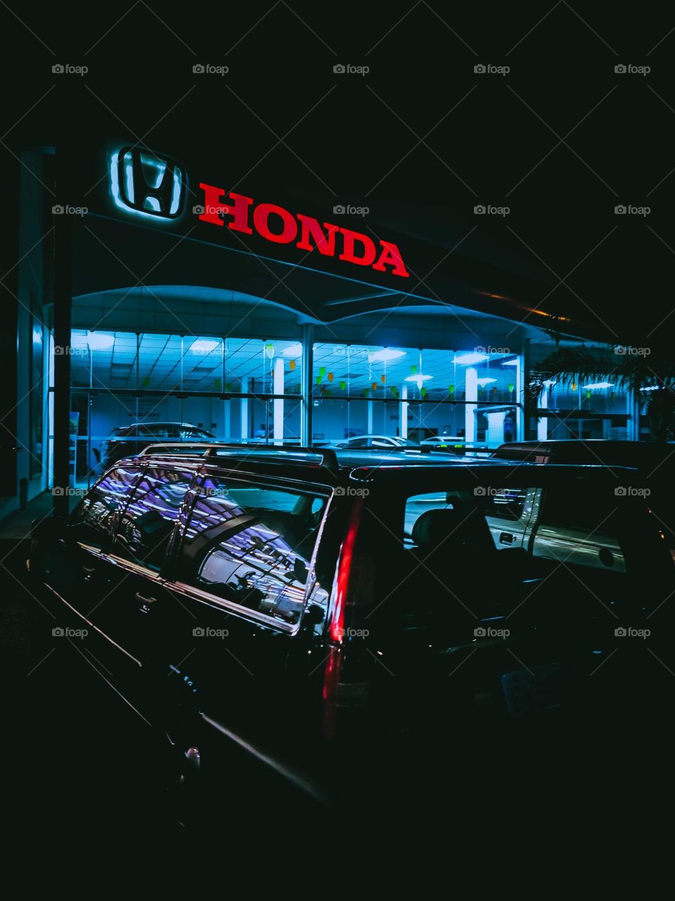 Nighttime photography of a Honda garage, with a retro Volvo wagon parked on the front, with beautiful colors and lights