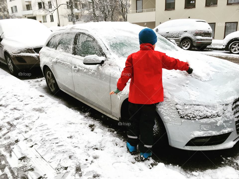 Boy brushes snow from car