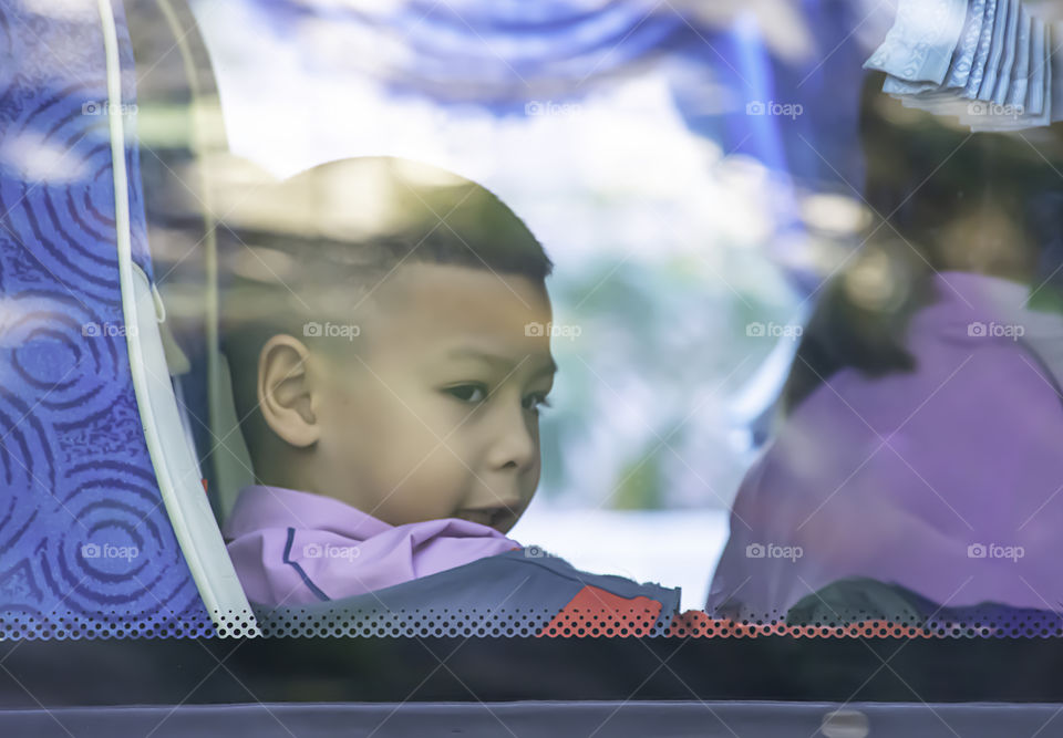 Asian boy sitting on a school bus.