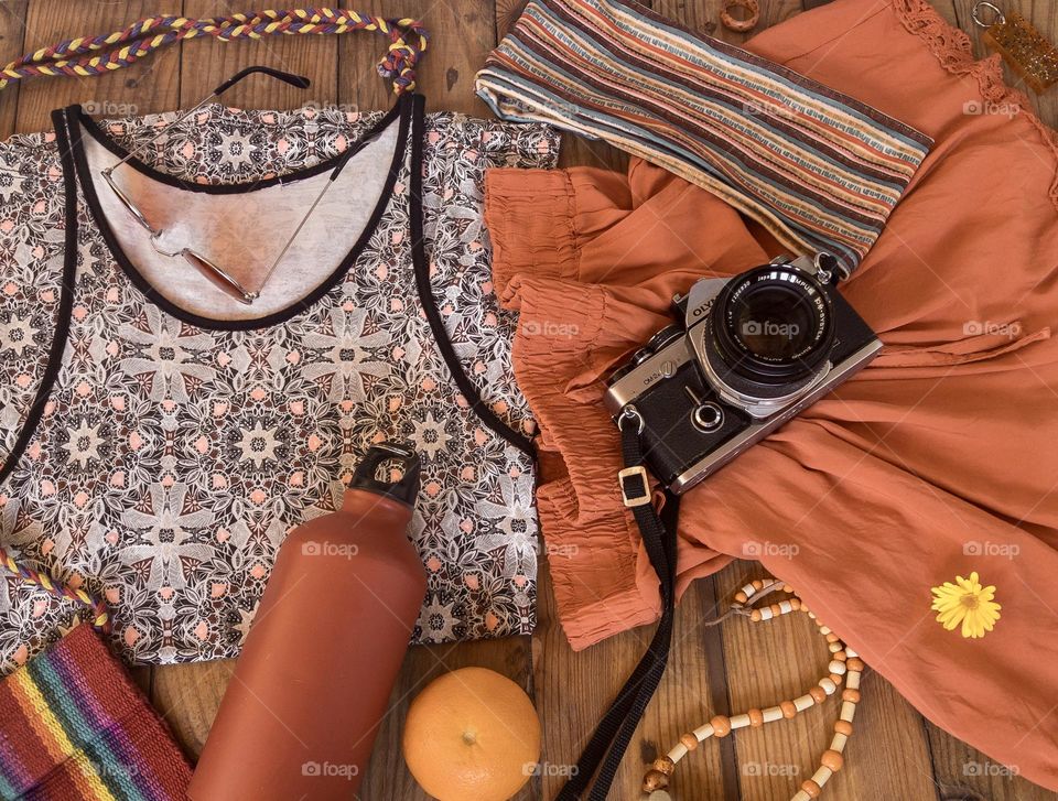 Summer day out flat lay featuring vest, shorts and accessories with water bottle, clementine and retro Olympus analog camera