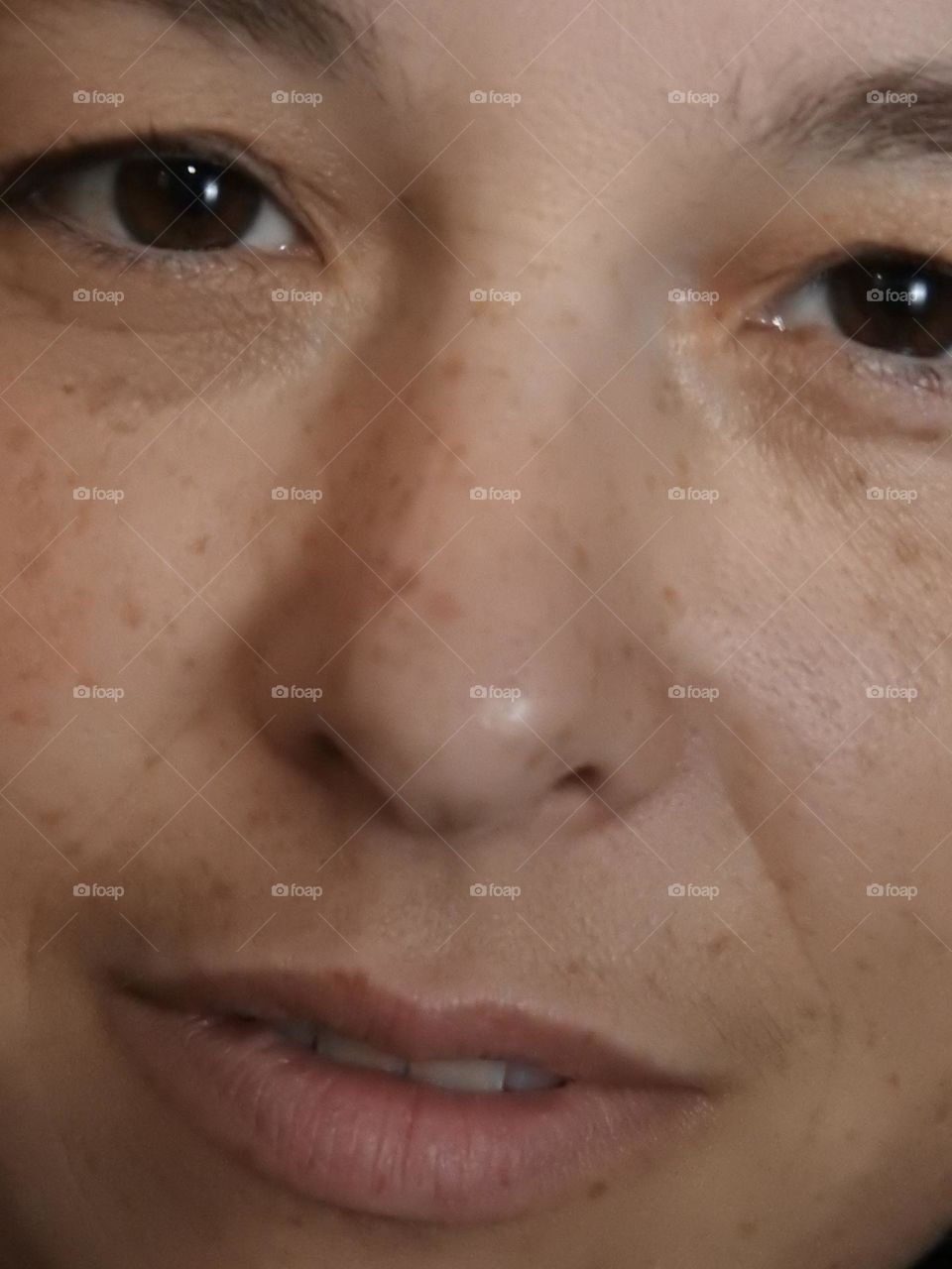 Face skin in the forties of a woman with freckles and brown hair closeup.