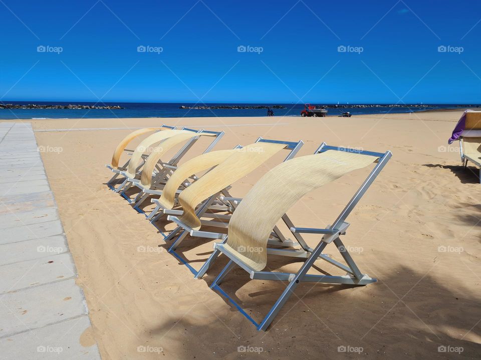 deck chairs in a row moved by the sea breeze