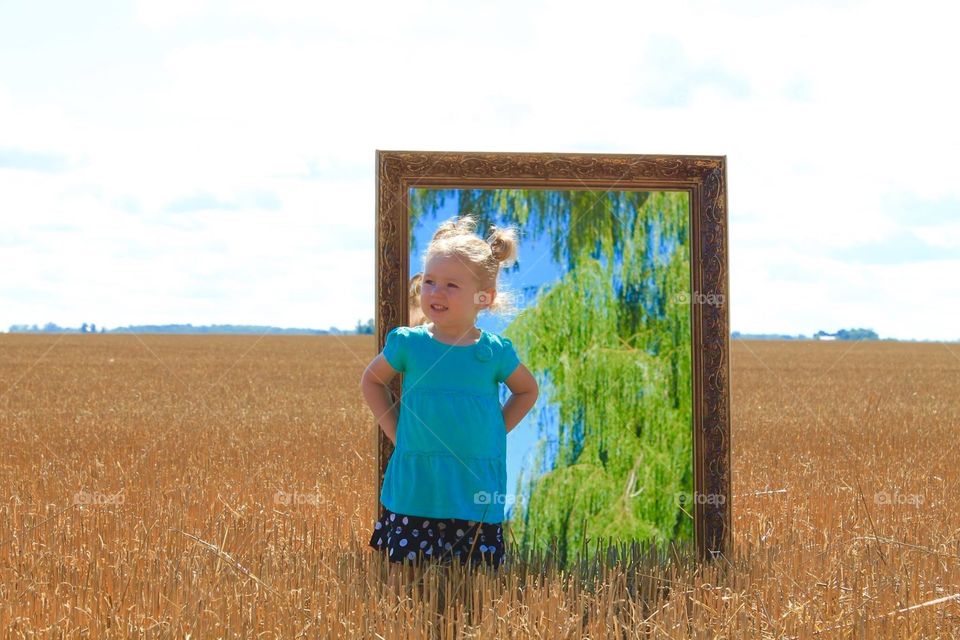 Girl with a mirror in dry grass field