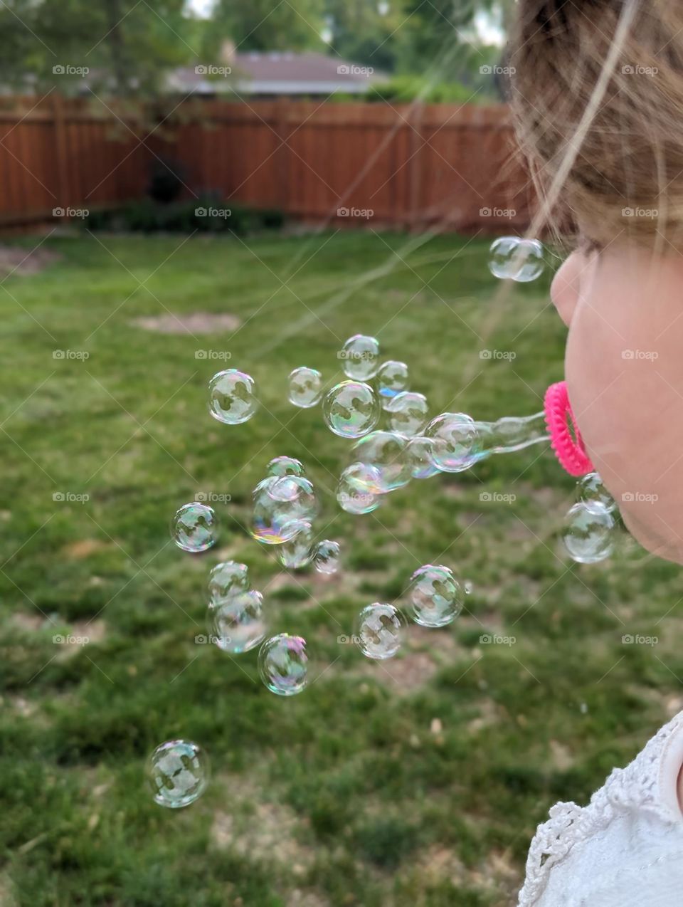 cute child blowing bubbles in the backyard on a warm spring day bubbles are a girl's best friend