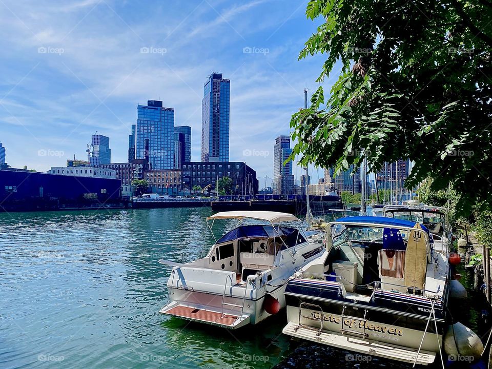 This is picturesque “Newtown Creek” by the “Pulaski Bridge” in LIC, Queens with a variety of boats tied to the shore and views that reach from “Greenpoint”, Bklyn to LIC to “Manhattan” including the “Empire State”. 2023. Hypnotic Productions