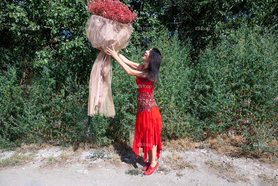 Woman Dances with a Large Bouquet of Red Flowers