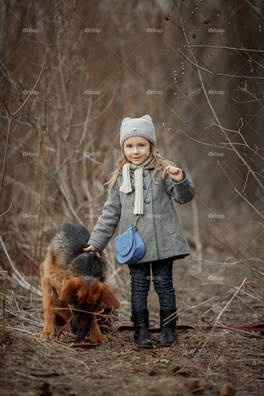 Little girl with German shepherd young male dog walking outdoor at spring day