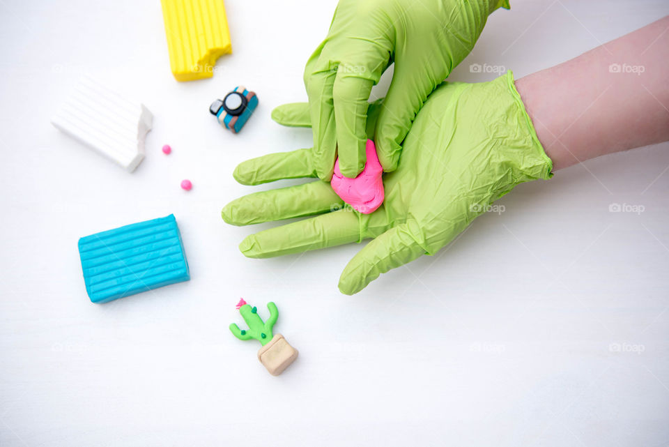 Person's gloved hands molding brightly colored clay