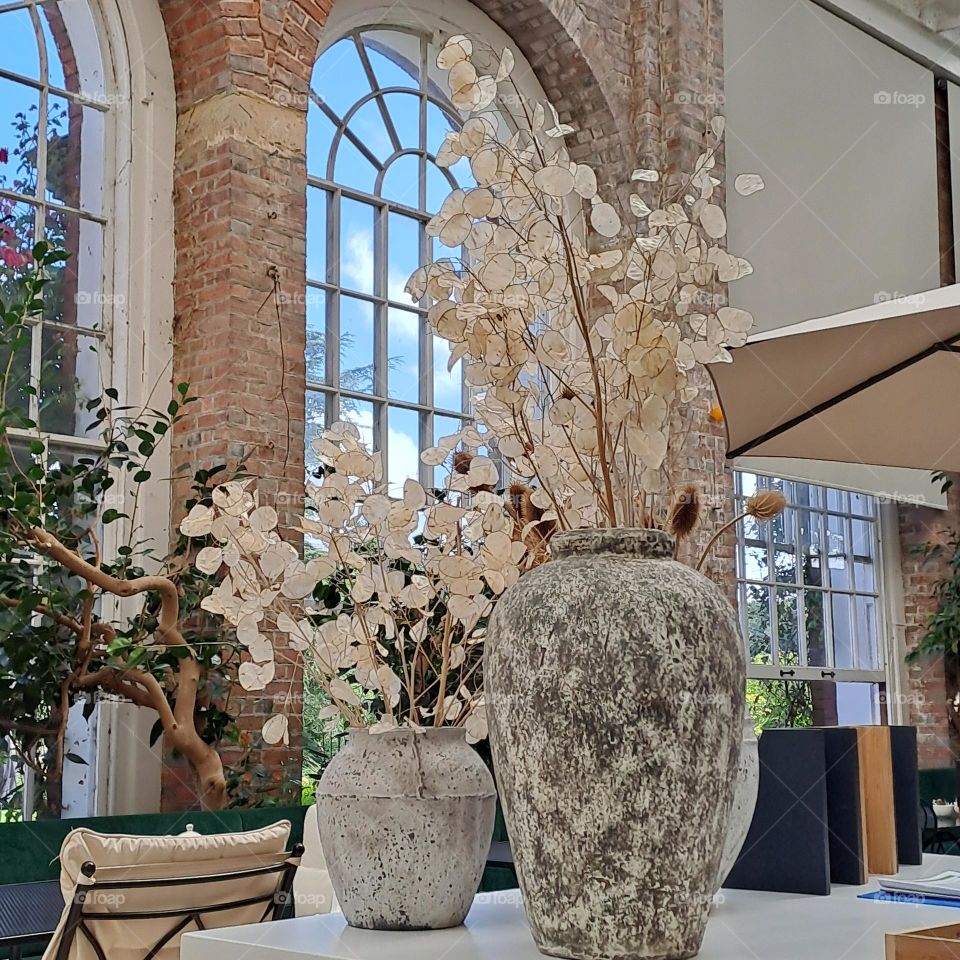 floral arrangement in orangery cafe large arch windows.  natural light tables vases