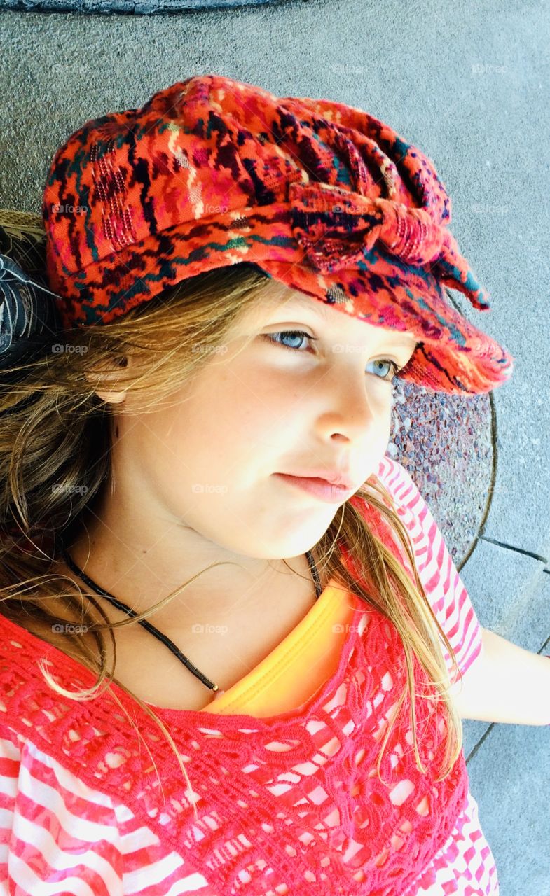 Gorgeous girl gazing into the sky with darling little plaid red hat on and red and white striped shirt. 