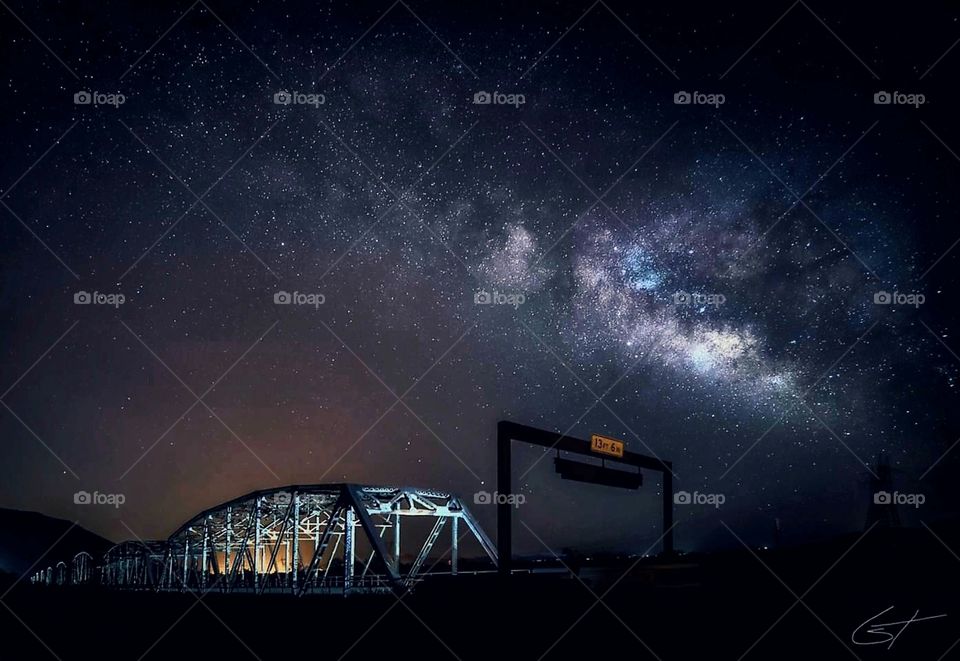 An Az. bridge is silhouetted against a sky so clear you can see the Milky Way