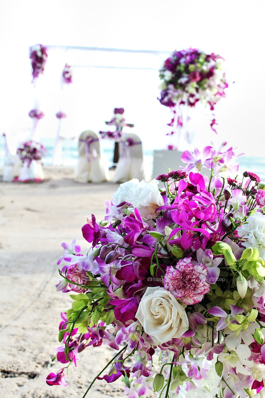 white and purple orchid floral arrangment at a beach wedding