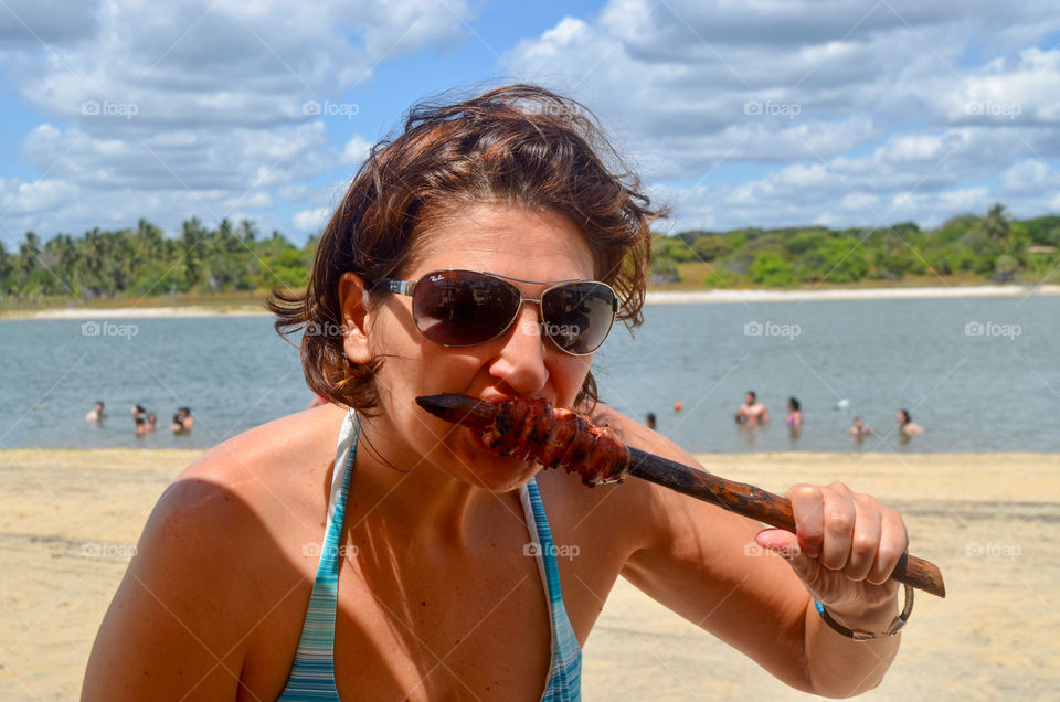 Woman eating sausage skewer