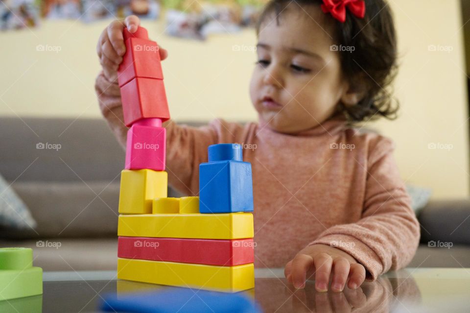 little girl playing rectangular colored constructions