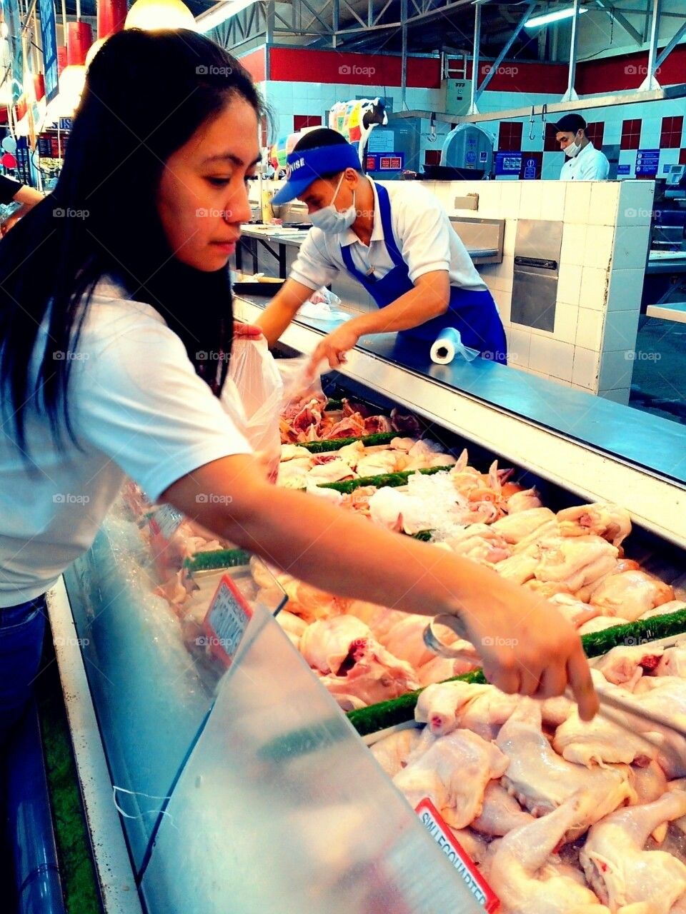 Customer selects chicken piece at a supermarket