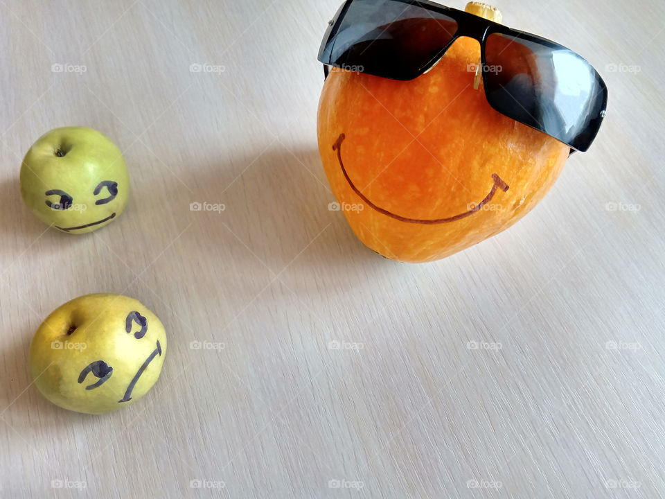 pumpkin in glasses lies on a wooden table among two apples