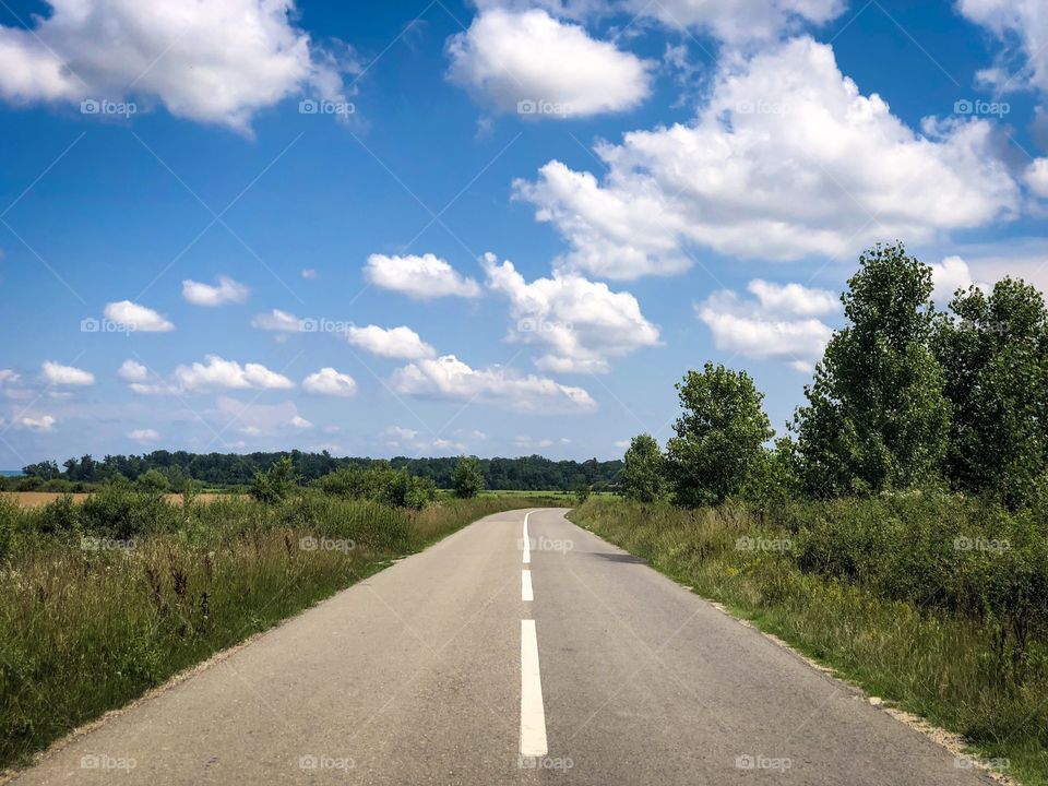 Empty road on a sunny day with blue sky and fluffy clouds