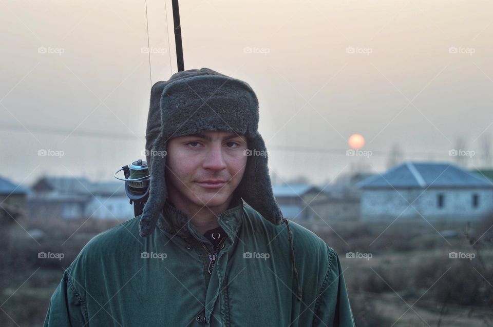 young fisherman in a hat with earflaps of a green jacket