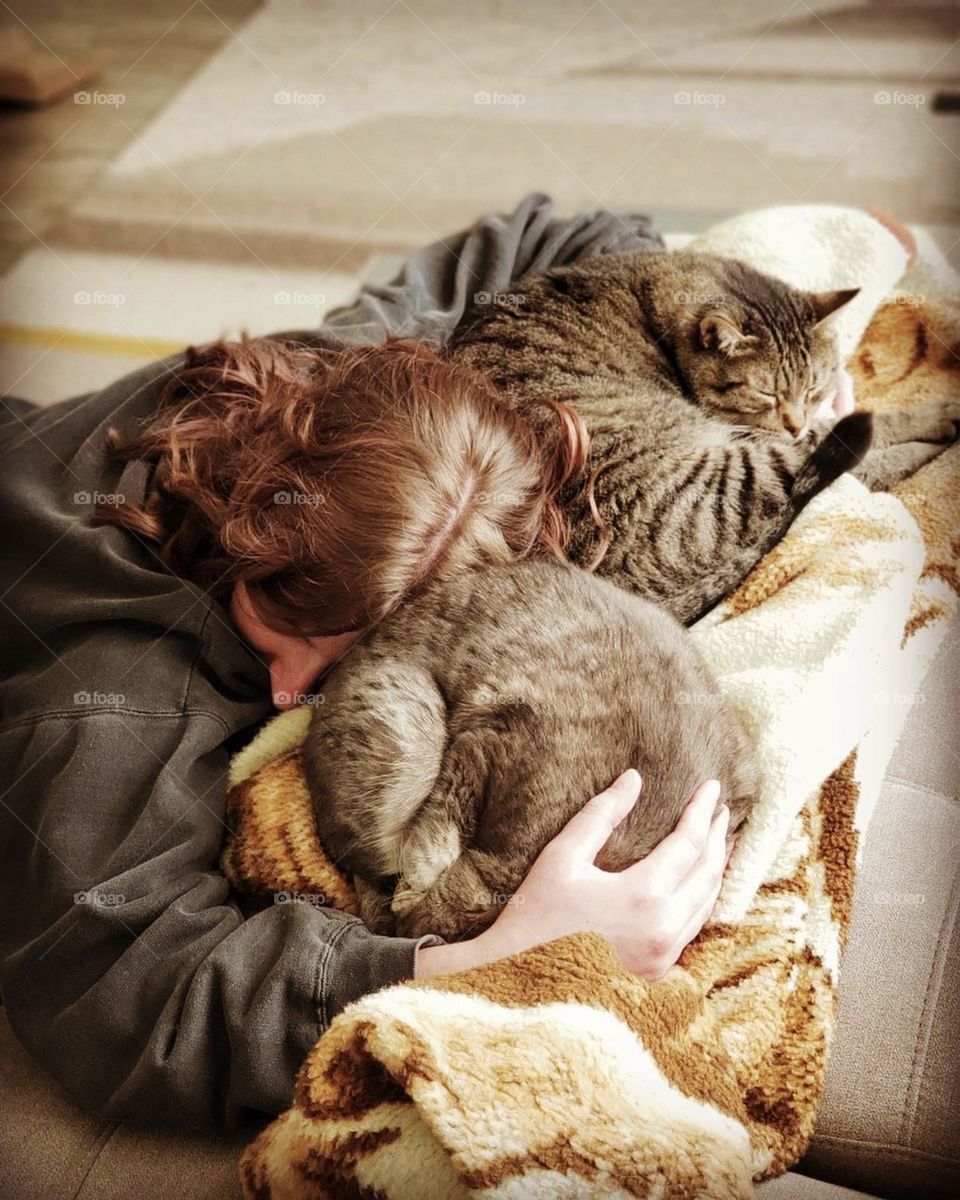 A woman hugs her sleeping cats in a peaceful moment of love