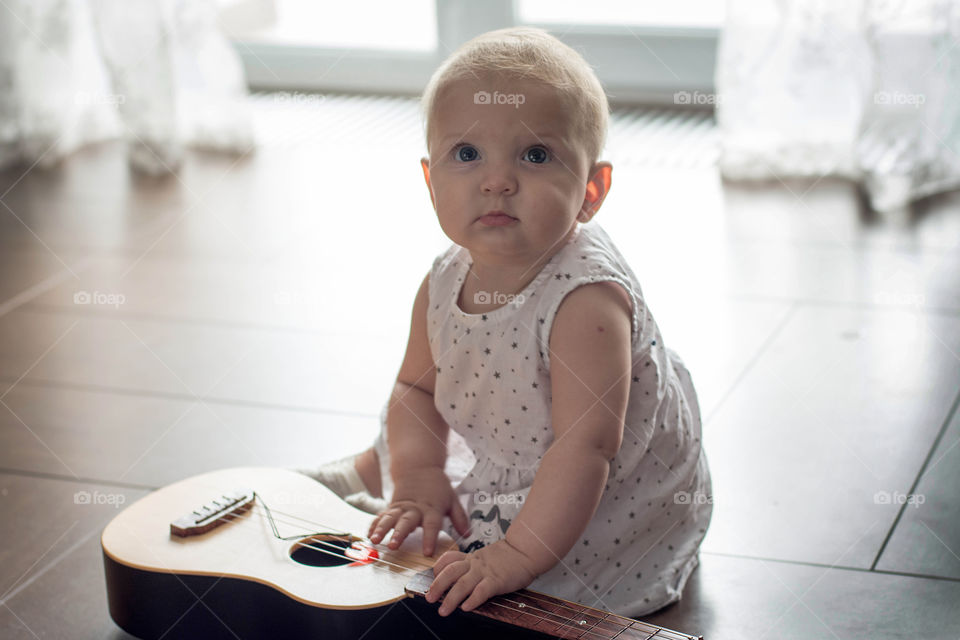 Cute little baby with guitar at home