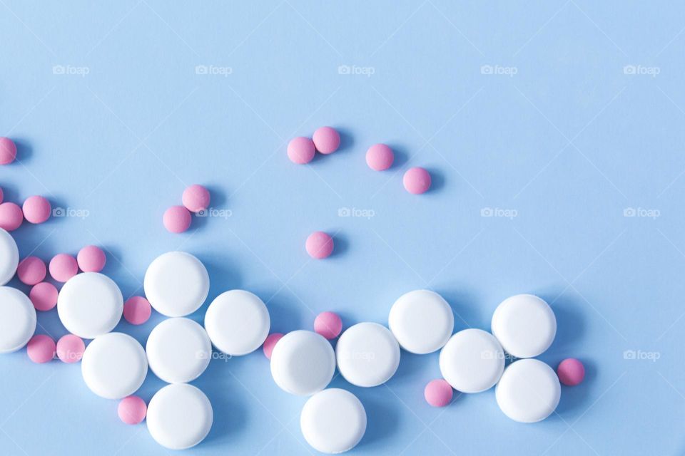 A large number of pills and medicines lie on a blue background.